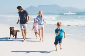 Familie macht Urlaub mit Hund am Strand
